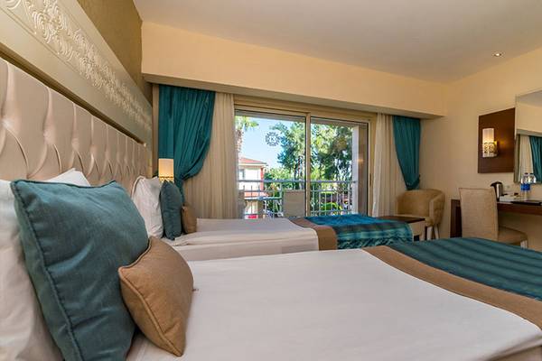 Zweibettzimmer im Kamelya Aishen K Club Hotel mit Betten, Dekor und Ausblick auf Terrasse.