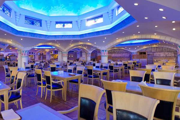 Innenbereich des Kamelya Aishen K Club Hotels, zeigt ein Restaurant mit blauen Deckenleuchten und Holztischen.