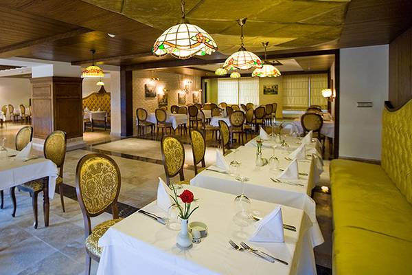 Innenansicht des Restaurants im Kamelya Aishen K Club mit gedeckten Tischen und farbigen Lampen.