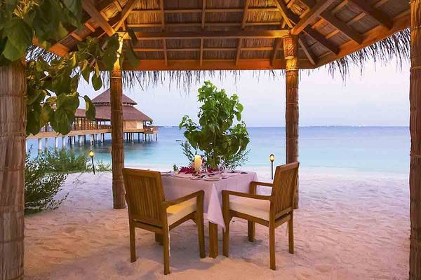Beeindruckendes Essen am Strand im Reethi Faru Resort mit Blick auf das Meer und eine Hütte.