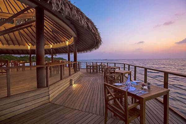 Terrasse des Reethi Faru Resorts mit Blick auf das Meer bei Sonnenuntergang