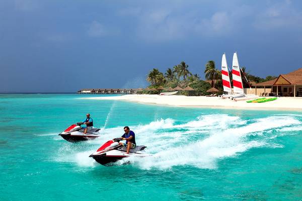 Zwei Männer auf Jet-Skis auf dem Meer im Reethi Faru Resort.