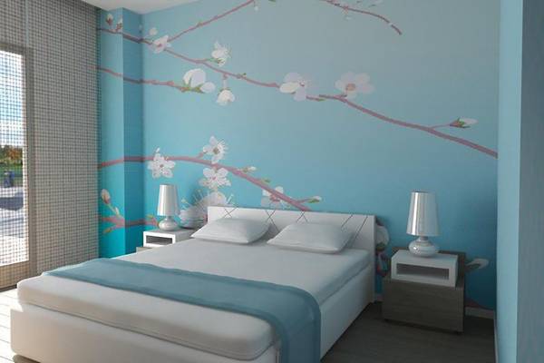 Schlafzimmer im Nestor Hotel mit blauer Wand und Kirschblütenmuster.