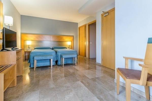 Innenansicht eines Doppelzimmers im Del Mar Hotel in Barcelona mit zwei Betten, Fernseher und Möbeln.