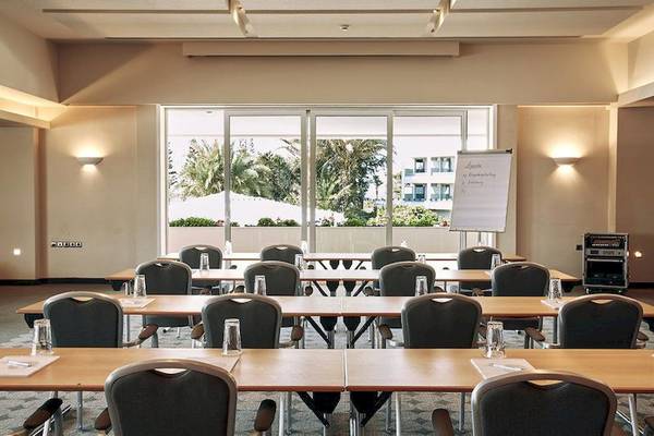 Konferenzraum im Robinson Kyllini Beach Hotel mit Blick auf eine weiße Tafel und Palmen draußen.