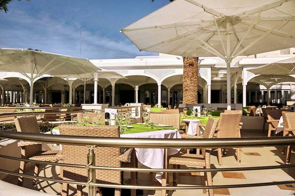 Außenterrasse des Robinson Kyllini Beach Hotels mit Tischen und Stühlen unter Schirmen.