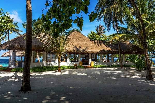 Das Amaya Kuda Rah Hotel mit einem großen, strohgedeckten Dach vor einer Palmenlandschaft.