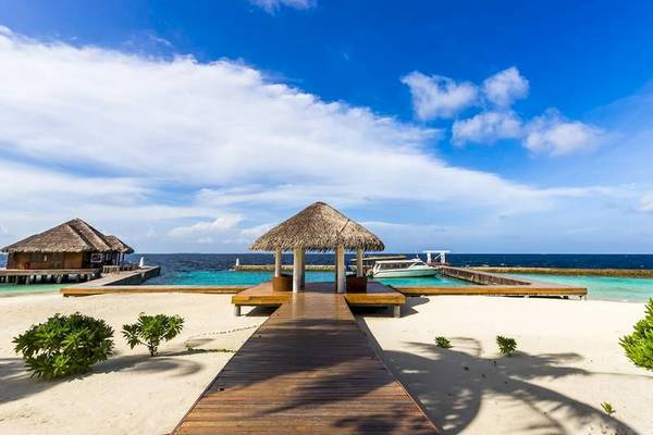 Amaya Kuda Rah Hotel Strand mit hütten und blauem Meer im Hintergrund