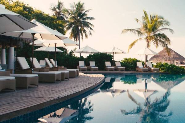 Pool-Loungebereich im Amaya Kuda Rah Hotel mit Sonnenliegen und Sonnenschirmen.