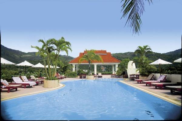 Poolbereich im The Old Phuket - Karon Beach Resort mit Loungeliegen und Sonnenschirmen.
