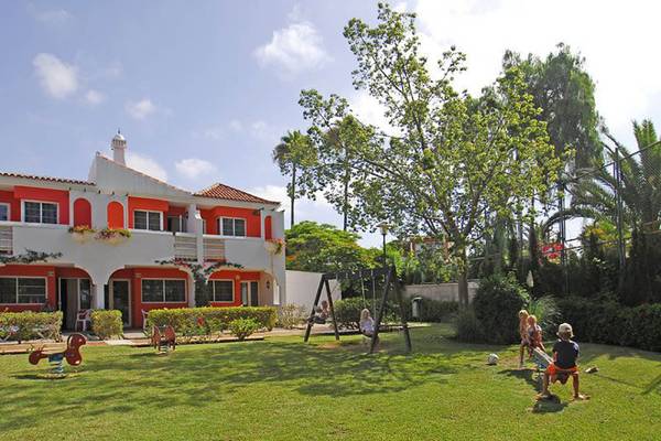 Außenbereich des Bungalows Cordial Green Golf mit Gebäude, Spielplatz und Kindern.