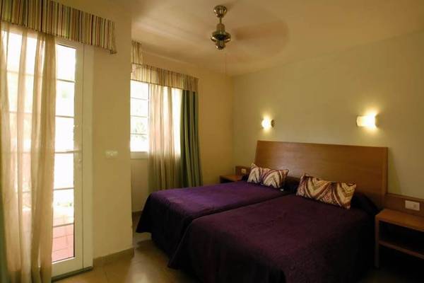 Schlafzimmer im Bungalows Cordial Green Golf mit zwei Betten, Nachttischen und Deckenventilator.