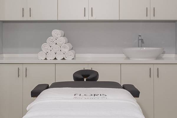 Ein Massagestuhl mit einem weißen Handtuch und einem Waschbecken in einem Zimmer