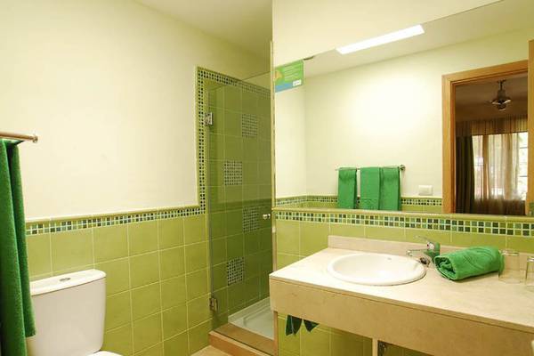 Grünes Badezimmer mit Toilette, Dusche und Waschbecken in den Bungalows Cordial Green Golf.