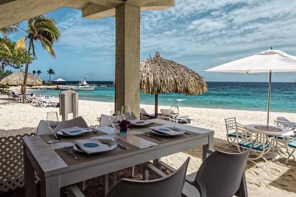 Ein Tisch auf dem Strand des Zoetry Curacao Resorts mit aufgestelltem Geschirr.