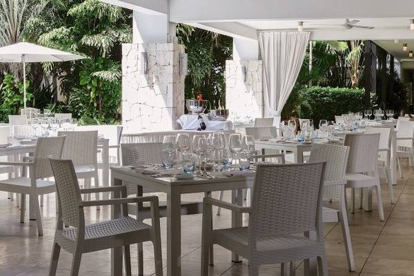 Außenrestaurant im Zoetry Curacao Resort & Spa mit weißen Möbeln und Vorhängen.