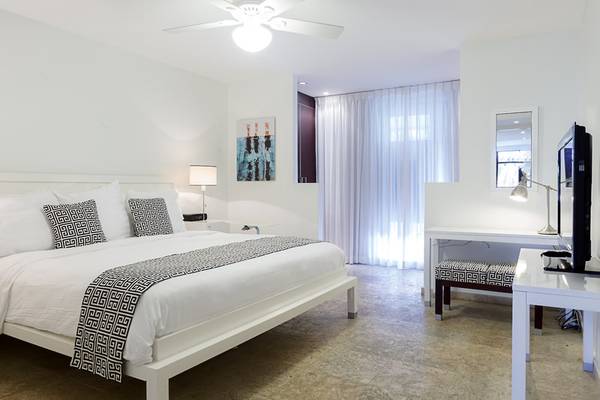 Schlafzimmer im Zoetry Curacao Resort & Spa mit weißen Möbeln und einem großen Bett.