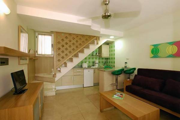 Innenansicht des Bungalows Cordial Green Golf mit Wohnbereich, Couch, Tisch, Fernseher und Treppe.