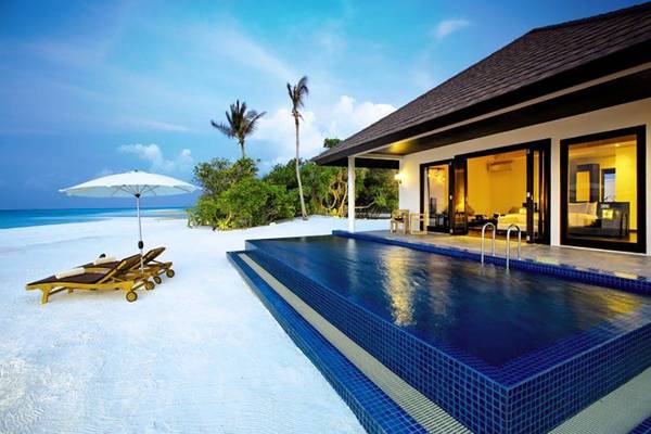 Villa mit Pool und Liegen am Strand von Atmosphere Kanifushi Maldives