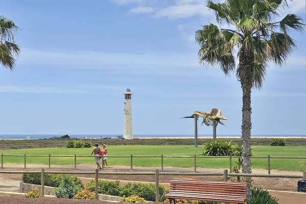 Leuchtturm im Hintergrund von Sol Fuerteventura Jandia Hotel, zwei Personen gehen auf dem Weg