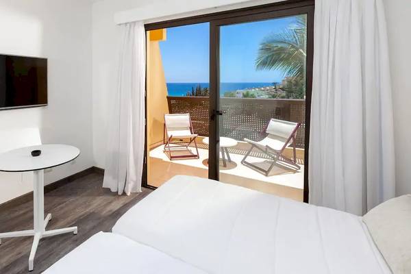 Ein Zimmer im Sol Fuerteventura Jandia Hotel mit Balkon, Fernseher, Tisch und Stühlen.