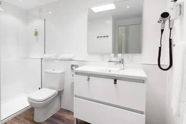 Ein modernes Badezimmer mit weißer Dusche, Toilette, Waschbecken und Spiegel im Sol Fuerteventura Jandia Hotel.