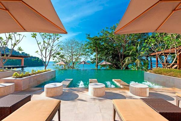 Pool-Terrasse im Westin Siray Bay Resort & Spa in Phuket mit Sonnenschirmen und Loungemöbeln.