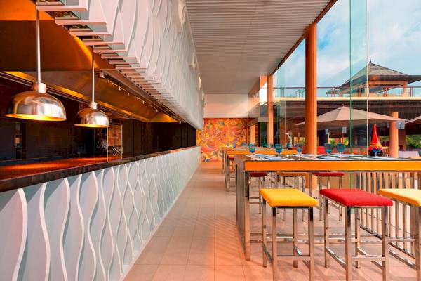 Innenansicht der Bar im Westin Siray Bay Resort & Spa, Phuket mit modernen Möbeln und bunten Wänden.