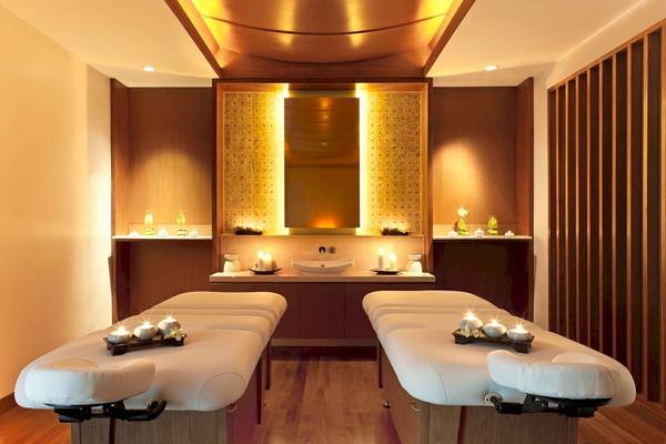 Massageraum im Westin Siray Bay Resort & Spa, Phuket, mit zwei Behandlungstischen und Kerzen.