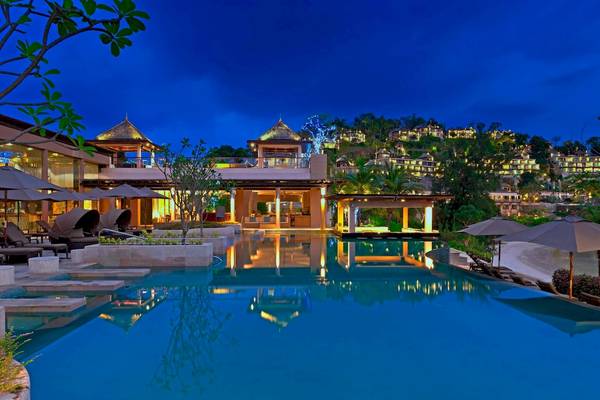 Der Westin Siray Bay Resort & Spa, Phuket, zeigt einen großen Poolbereich mit Sonnenliegen und Sonnenschirmen, der bei Nachtbeleuchtung beeindruckend ist.