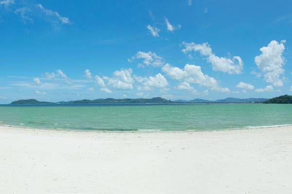 Strand des Westin Siray Bay Resorts in Phuket mit blauem Himmel und weißen Wolken
