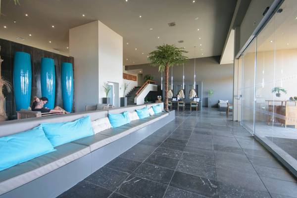 Lobby des Oasis Salinas Sea Hotels mit langen grauen Sofas, blauen Kissen und großen blauen Säulen.
