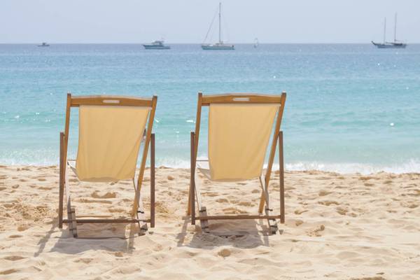 Zwei Liegestühle auf dem Strand mit Booten im Hintergrund im Oasis Salinas Sea Hotel.