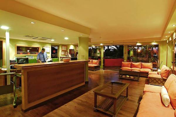 Rezeption Bereich im Bungalows Cordial Green Golf Hotel mit Holzmöbeln und einer Person am Empfang