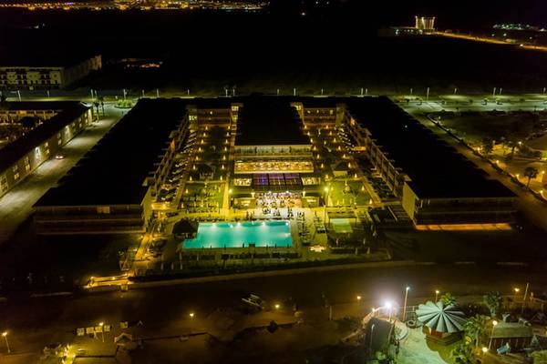 Abendansicht des Oasis Salinas Sea Hotels mit beleuchtetem Swimmingpool und Gebäuden.