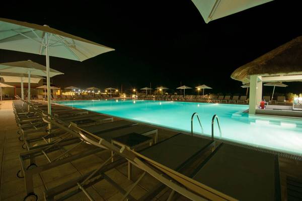 Außenpool des Oasis Salinas Sea Hotels bei Nacht mit Liegen und Schirmen