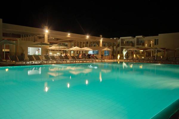 Pool des Oasis Salinas Sea Hotels bei Nacht mit beleuchteten Sonnenschirmen und Liegestühlen.
