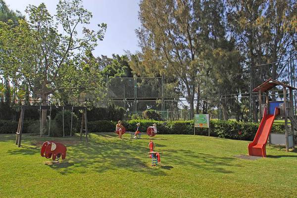 Kinderspielplatz im Hotel Bungalows Cordial Green Golf mit Rutsche und Schaukeln.