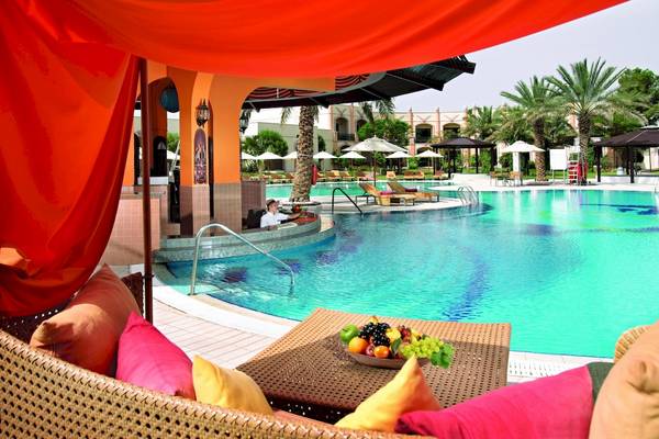 Außenpoolterrasse des Al Ain Rotana Hotels mit Obstschale und Loungemöbeln.
