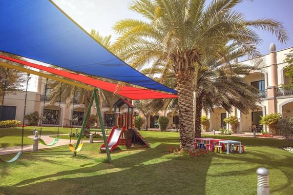 Kinderspielplatz im Freien vor dem Al Ain Rotana Hotel mit Rutsche und Schaukeln.