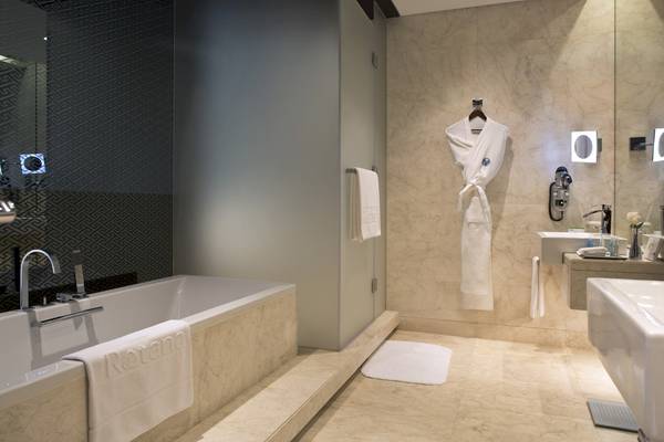 Badezimmer im Al Ain Rotana Hotel mit Badewanne, Handtüchern und Waschbecken.