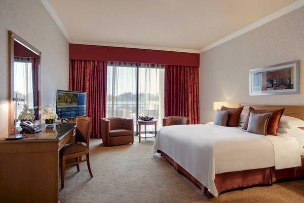 Ein elegantes Hotelzimmer im Al Ain Rotana mit einem großen Bett, einem Fernseher und einem Schreibtisch.