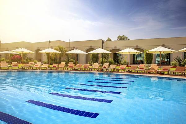 Außenpool des Al Ain Rotana Hotels mit Liegestühlen und Sonnenschirmen