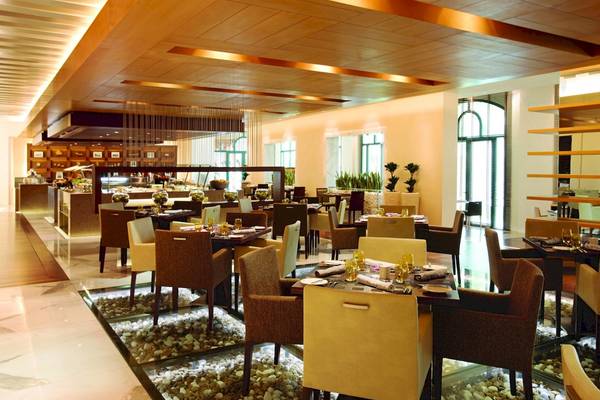 Innenansicht des Al Ain Rotana Restaurants mit runden Tischen und Stühlen.