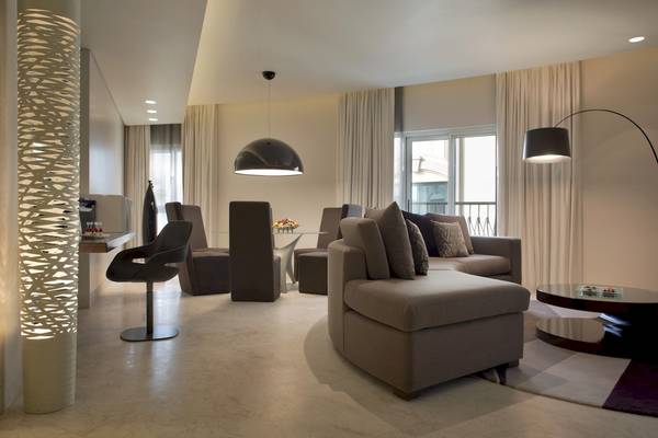 Wohnzimmer des Al Ain Rotana Hotels mit moderner Einrichtung, Sofas, Tischen und Lampen.