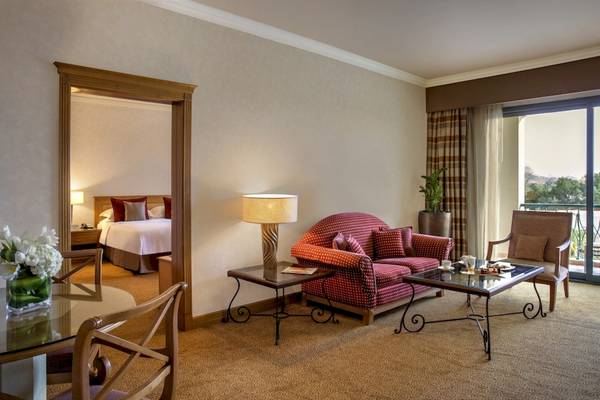 Innenansicht einer Suite im Al Ain Rotana Hotel mit Wohnzimmer, Schlafzimmer und Balkon.