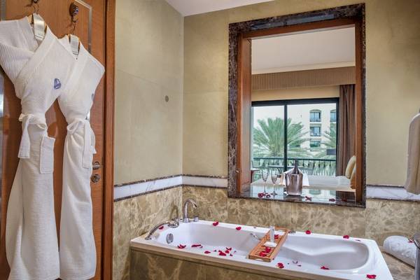 Badezimmer des Al Ain Rotana Hotels mit Badewanne und Rosenblättern