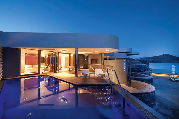 Nachtansicht des Elounda Beach Hotel & Villas mit beleuchtetem Pool und Außenbereich.