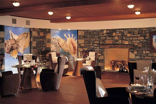 Innenbereich des Elounda Beach Hotel & Villas mit Steinwänden, Tischen und Stühlen.