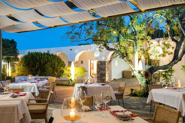 Abendstimmung im Freien Restaurant des Elounda Beach Hotel & Villas mit beleuchteten Tischen und hängenden Vorhängen.